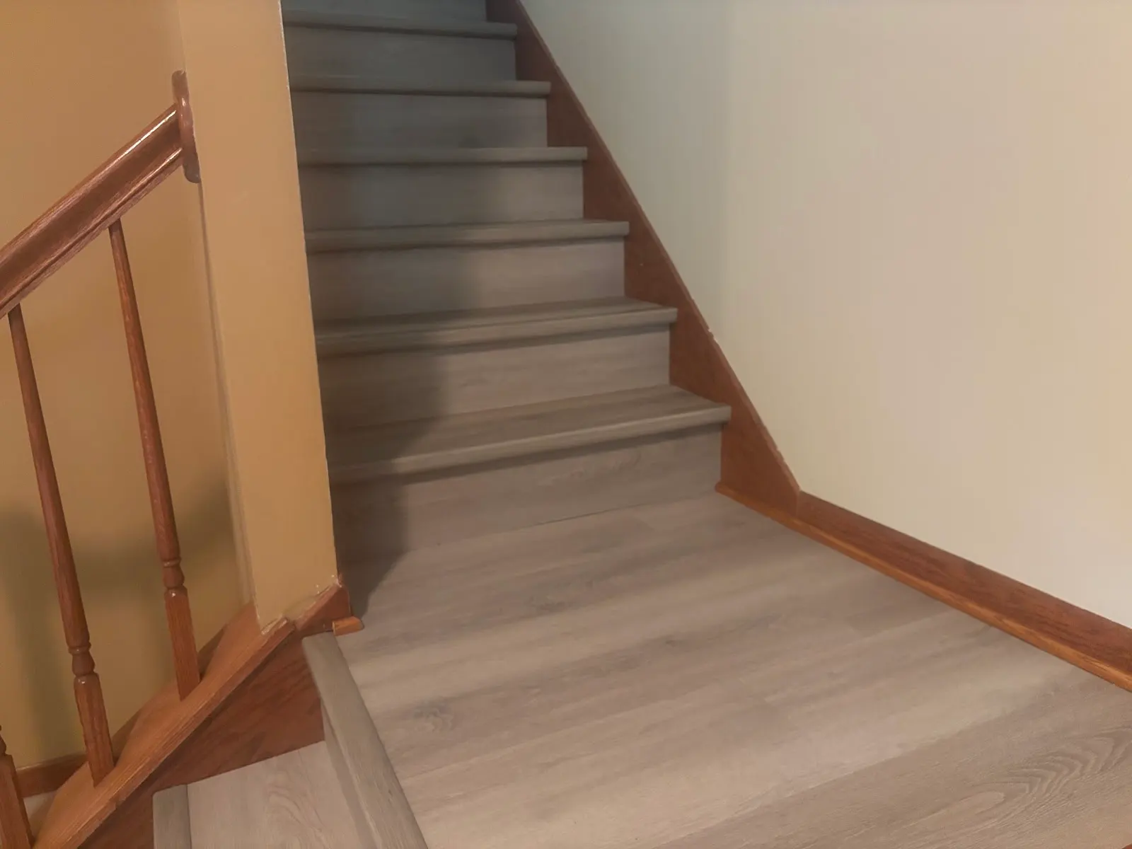 Gray luxury vinyl plank stairs and landing with oak handrail and trim